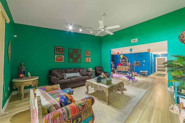 living room featuring baseboards, visible vents, ceiling fan, wood finished floors, and vaulted ceiling