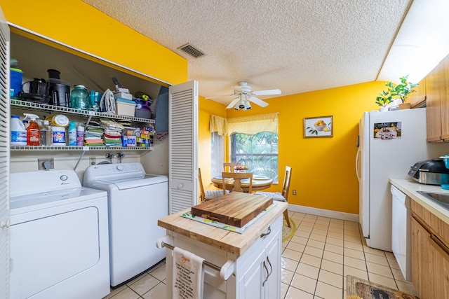 laundry area featuring a textured ceiling, light tile patterned flooring, laundry area, separate washer and dryer, and visible vents