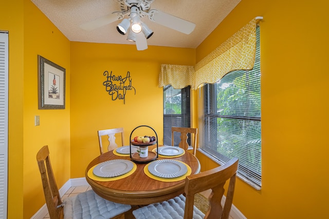 tiled dining room featuring a ceiling fan, a textured ceiling, and baseboards