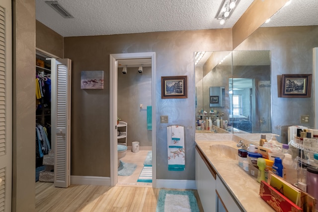 full bathroom featuring visible vents, vanity, a textured ceiling, and wood finished floors