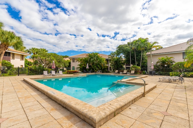 community pool with a patio and fence