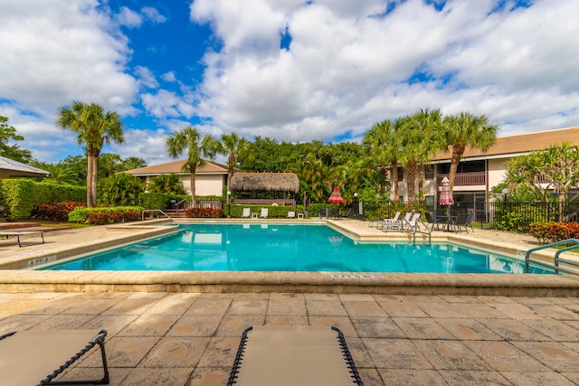 community pool with a patio area and fence