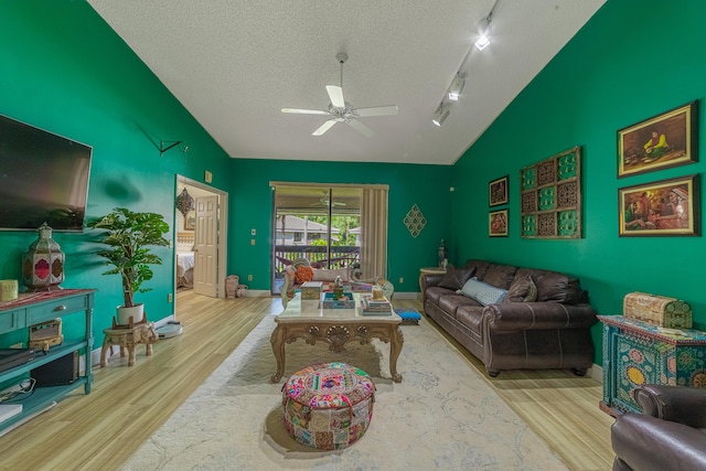 living area featuring lofted ceiling, a textured ceiling, wood finished floors, and a ceiling fan