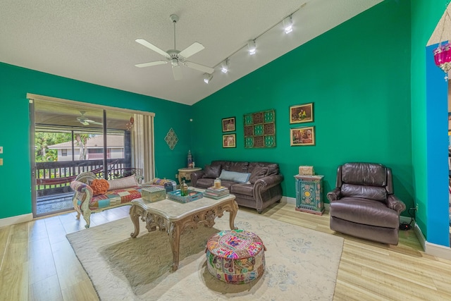 living room with ceiling fan, a textured ceiling, baseboards, and wood finished floors