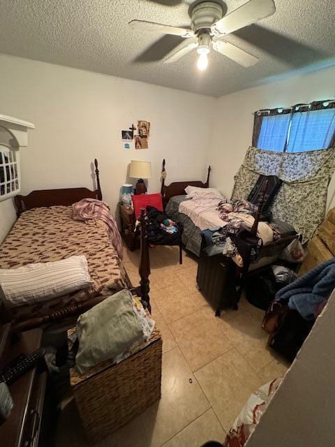 bedroom featuring a textured ceiling, light tile patterned floors, and ceiling fan