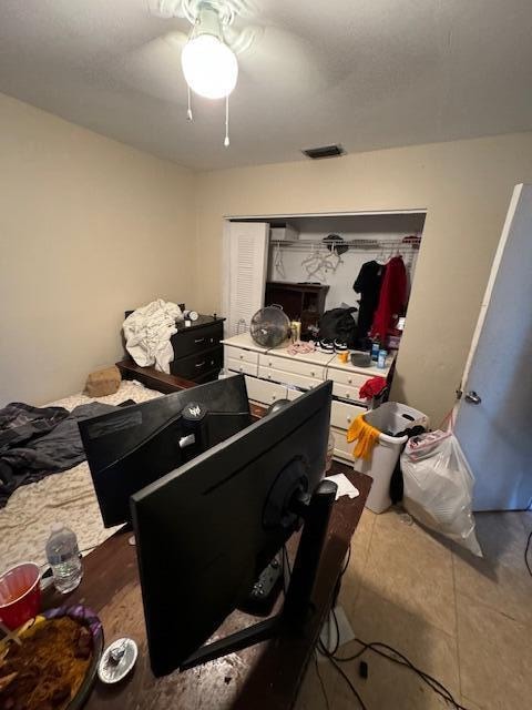 bedroom featuring a closet, dark tile patterned floors, and ceiling fan