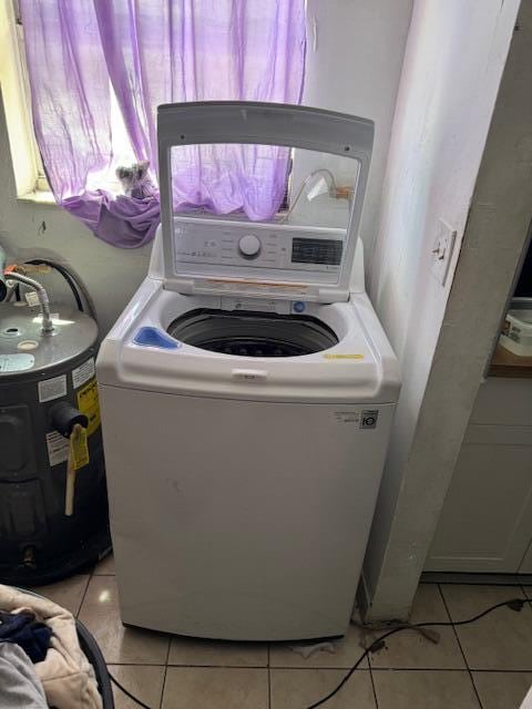 washroom with washer / dryer, water heater, and light tile patterned flooring