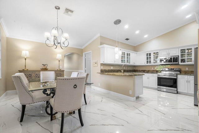 kitchen with white cabinetry, hanging light fixtures, vaulted ceiling, and stainless steel appliances