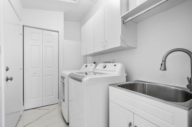 laundry area featuring cabinets, sink, washer and dryer, and a textured ceiling