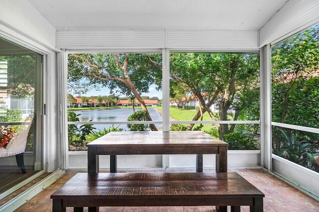 sunroom featuring a water view