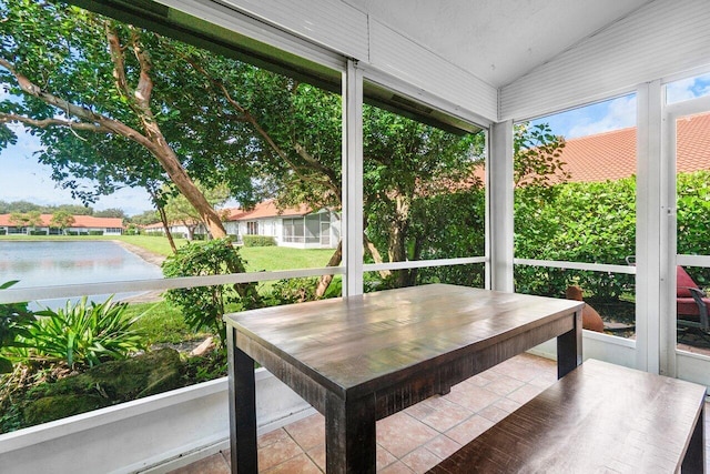 sunroom featuring a water view and vaulted ceiling