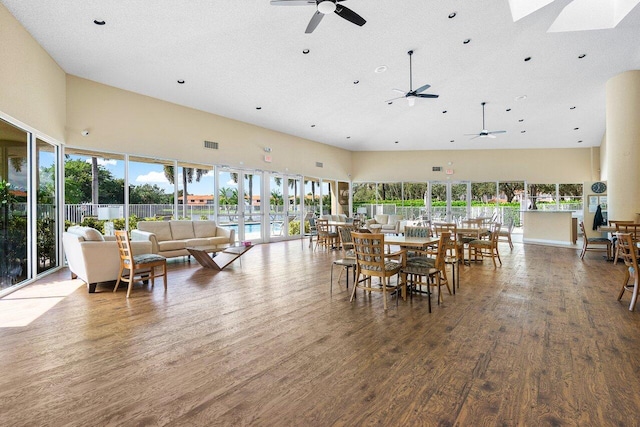 dining space featuring a textured ceiling, hardwood / wood-style flooring, and a towering ceiling