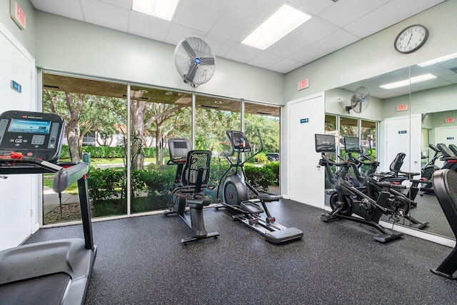 exercise room with a paneled ceiling and plenty of natural light