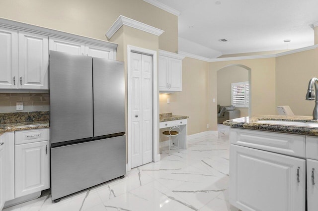 kitchen featuring stainless steel refrigerator, white cabinetry, sink, tasteful backsplash, and crown molding