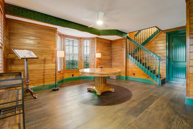 interior space featuring ceiling fan, wood-type flooring, and wood walls