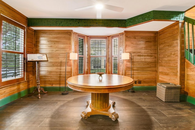 dining area featuring ceiling fan and wood walls