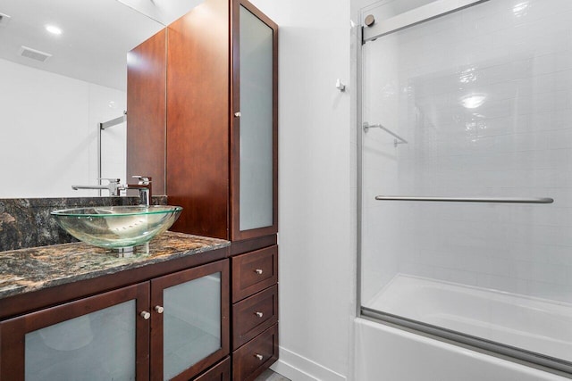 bathroom with bath / shower combo with glass door and vanity