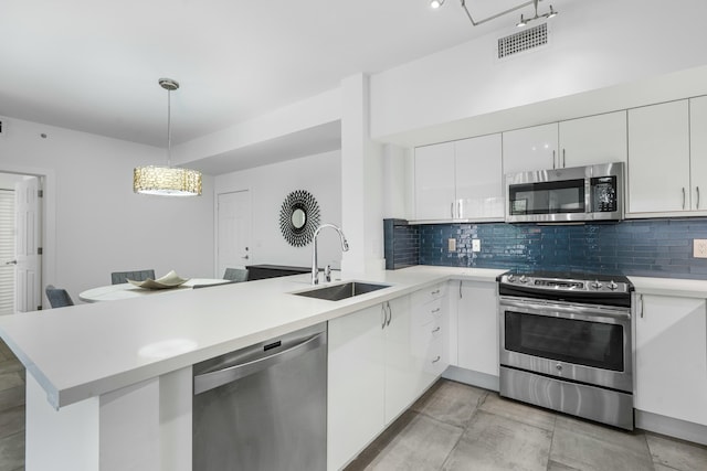 kitchen featuring appliances with stainless steel finishes, decorative light fixtures, kitchen peninsula, and sink