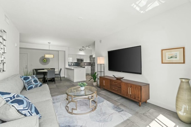 living room featuring rail lighting and sink