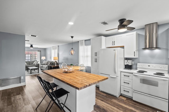 kitchen featuring dark wood-type flooring, a breakfast bar area, wall chimney range hood, white cabinetry, and white appliances