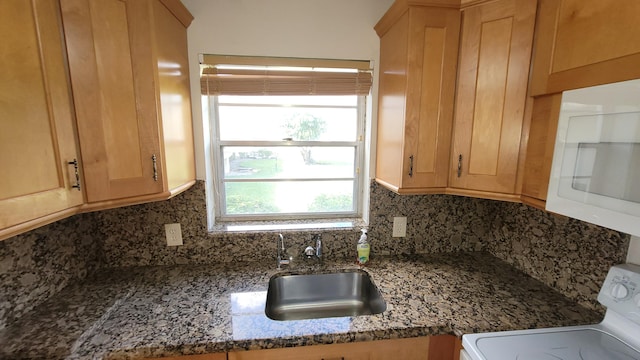 kitchen with dark stone countertops, tasteful backsplash, sink, and stove