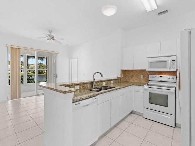 kitchen with white appliances, dark stone counters, white cabinets, sink, and kitchen peninsula