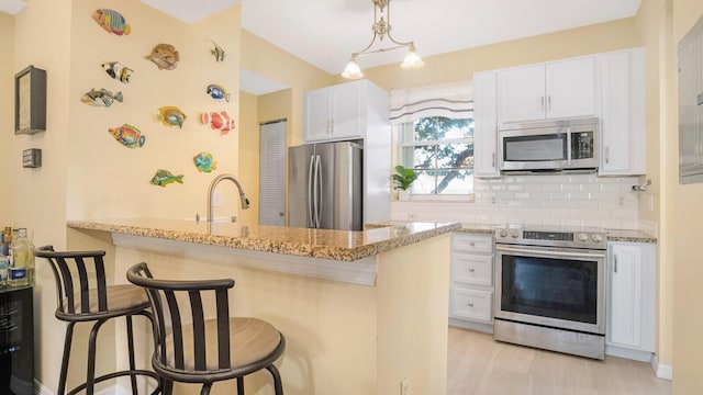 kitchen featuring a kitchen breakfast bar, white cabinetry, kitchen peninsula, and stainless steel appliances