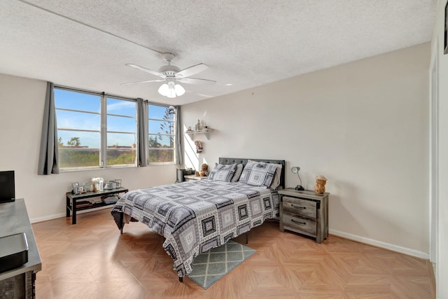 bedroom featuring ceiling fan, light parquet floors, and a textured ceiling