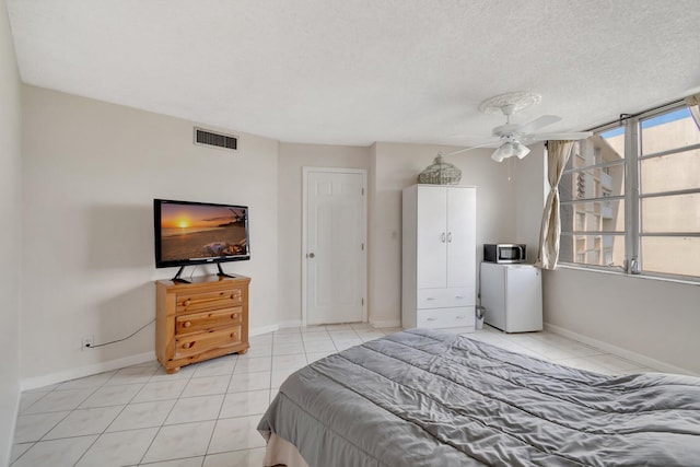 bedroom with ceiling fan, light tile patterned flooring, and a textured ceiling