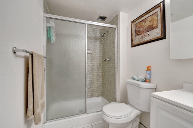 bathroom featuring tile patterned floors, vanity, a shower with shower door, and toilet