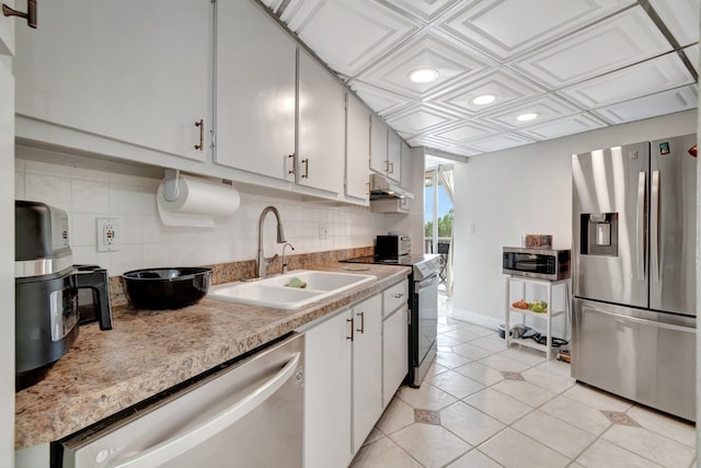 kitchen featuring appliances with stainless steel finishes, tasteful backsplash, sink, light tile patterned floors, and white cabinets