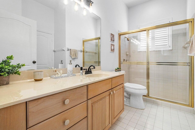 bathroom featuring tile patterned flooring, vanity, toilet, and a shower with shower door