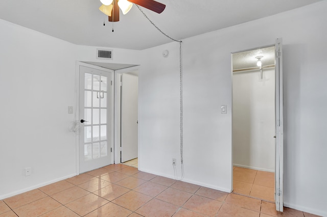 unfurnished bedroom with a walk in closet, ceiling fan, a closet, and light tile patterned floors