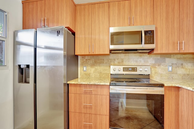 kitchen with tile patterned flooring, light stone counters, backsplash, and appliances with stainless steel finishes