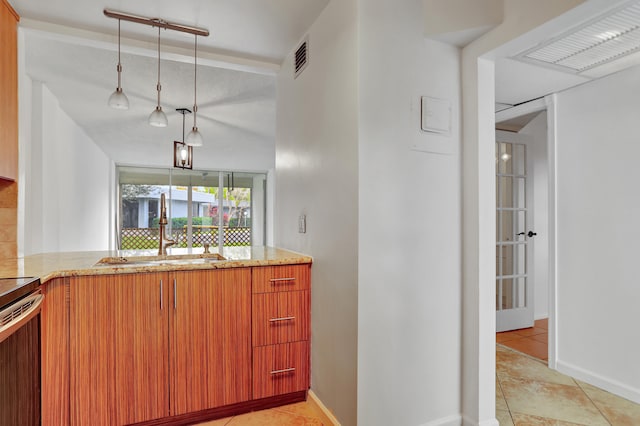 kitchen with pendant lighting, kitchen peninsula, light tile patterned floors, and sink