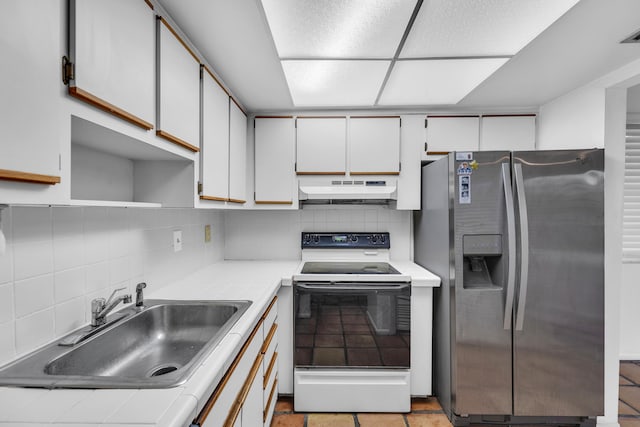 kitchen featuring stainless steel fridge, backsplash, sink, white electric range, and white cabinetry