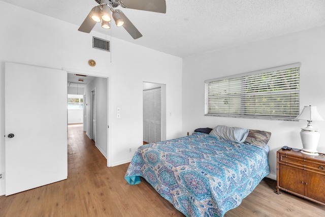 bedroom featuring a closet, ceiling fan, light hardwood / wood-style flooring, and a textured ceiling