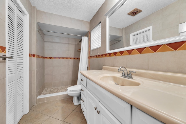 bathroom featuring tile patterned flooring, vanity, a textured ceiling, and tile walls