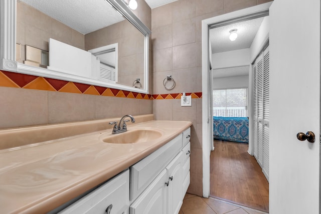 bathroom with vanity, wood-type flooring, a textured ceiling, and tile walls