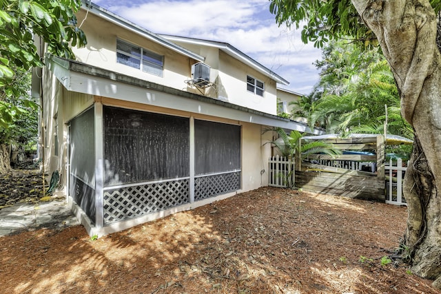 1912 NE 6th St, Deerfield Beach, FL 33441 - view of side of property with a sunroom, stucco siding, central air condition unit, and fence
