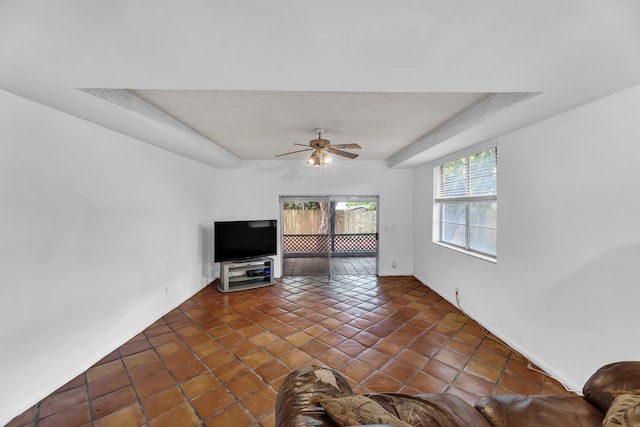 unfurnished living room with dark tile patterned flooring, ceiling fan, and a textured ceiling