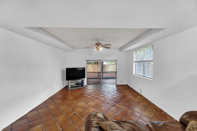 1912 NE 6th St, Deerfield Beach, FL 33441 - unfurnished living room featuring a ceiling fan, a tray ceiling, tile patterned floors, baseboards, and a textured ceiling