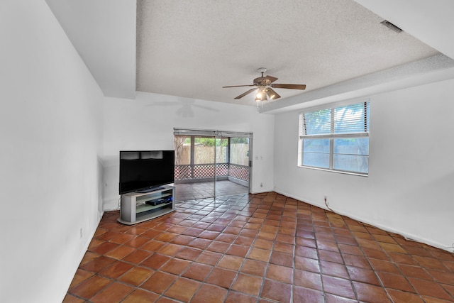 living room featuring ceiling fan, dark tile patterned floors, and a textured ceiling