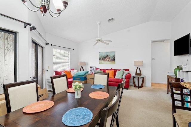 carpeted dining area with ceiling fan with notable chandelier, lofted ceiling, and a textured ceiling