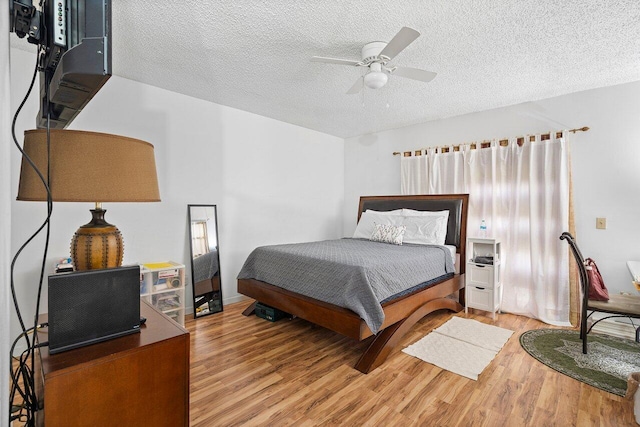 bedroom with hardwood / wood-style floors, ceiling fan, and a textured ceiling