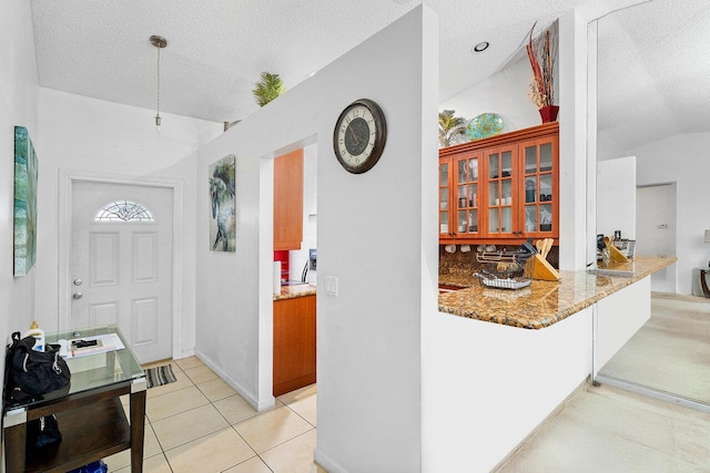 interior space with kitchen peninsula, a textured ceiling, and vaulted ceiling