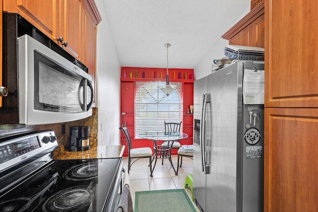 kitchen featuring appliances with stainless steel finishes, a textured ceiling, light tile patterned floors, hanging light fixtures, and lofted ceiling