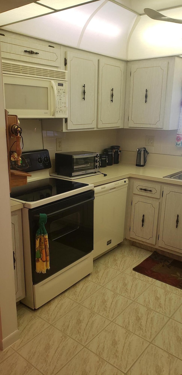 kitchen with cream cabinets, decorative backsplash, sink, light tile patterned flooring, and white appliances