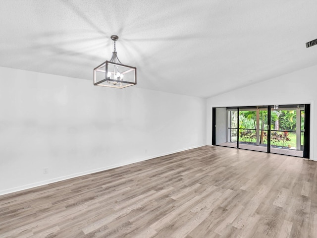 interior space with light hardwood / wood-style floors, a textured ceiling, lofted ceiling, and a notable chandelier