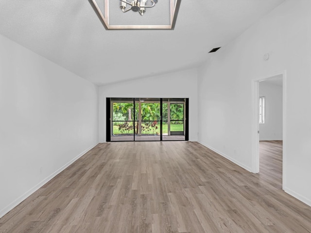 unfurnished living room with a chandelier, light wood-type flooring, and lofted ceiling